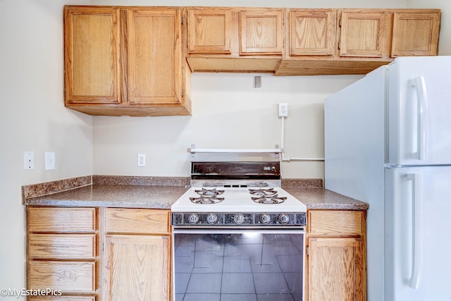 kitchen featuring tile patterned floors, light brown cabinets, and white appliances