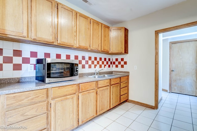 kitchen with light tile patterned flooring, sink, light brown cabinets, and tasteful backsplash