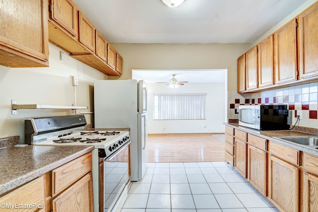 kitchen with white appliances, decorative backsplash, sink, light tile patterned flooring, and ceiling fan