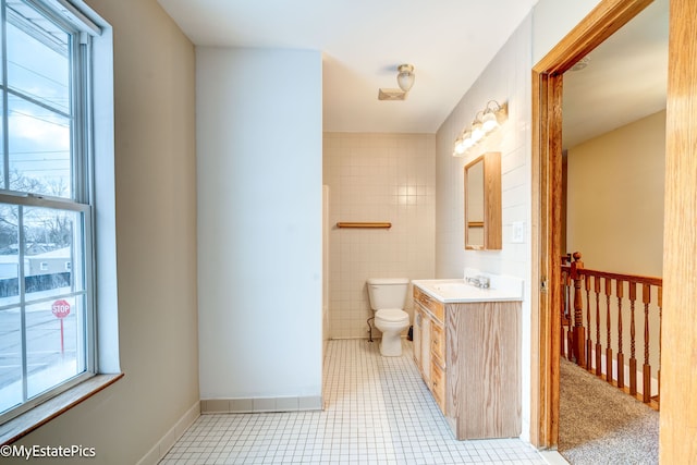 bathroom with toilet, tile walls, tile patterned floors, and vanity