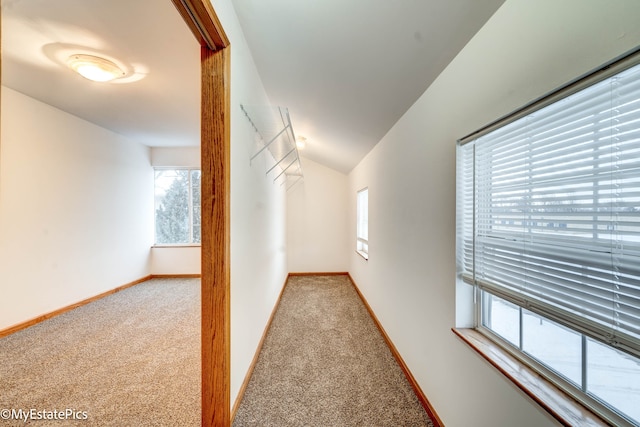 corridor with vaulted ceiling and carpet flooring