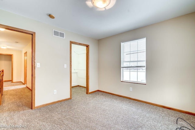 unfurnished bedroom featuring a closet, a walk in closet, and carpet flooring