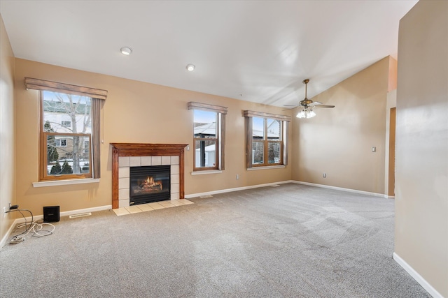 unfurnished living room featuring vaulted ceiling, ceiling fan, light carpet, and a tiled fireplace