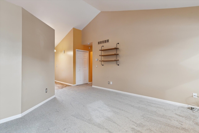 carpeted empty room with high vaulted ceiling