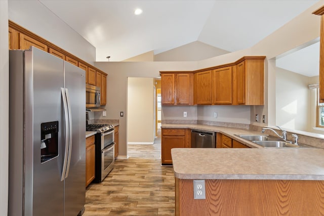 kitchen featuring kitchen peninsula, light hardwood / wood-style flooring, sink, lofted ceiling, and stainless steel appliances