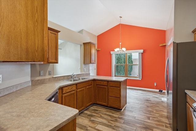 kitchen featuring kitchen peninsula, pendant lighting, appliances with stainless steel finishes, sink, and lofted ceiling