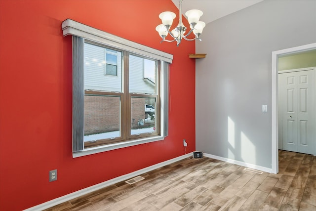 empty room with a chandelier and wood-type flooring