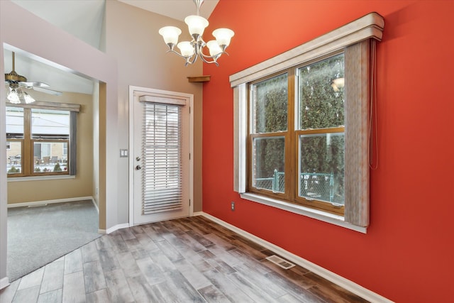 doorway with wood-type flooring, a healthy amount of sunlight, and ceiling fan with notable chandelier