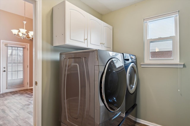 washroom featuring washing machine and dryer, light wood-type flooring, an inviting chandelier, and cabinets