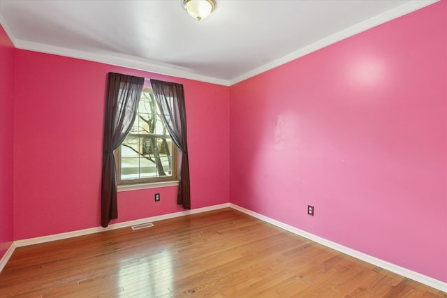 empty room with ornamental molding and hardwood / wood-style floors