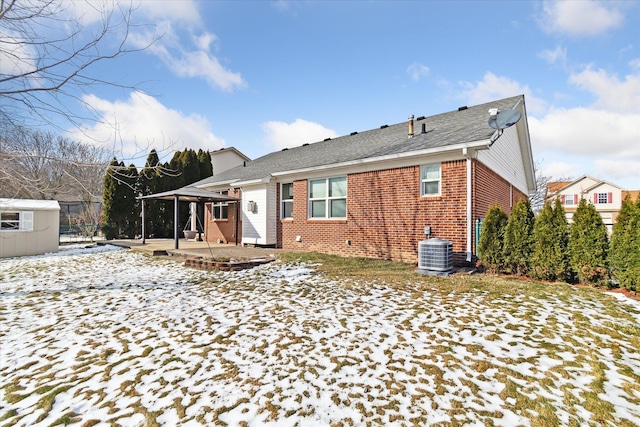 snow covered back of property featuring central air condition unit, a gazebo, and a patio