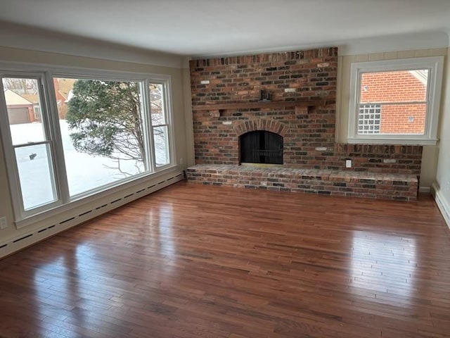 unfurnished living room featuring dark hardwood / wood-style flooring, a fireplace, and a baseboard heating unit