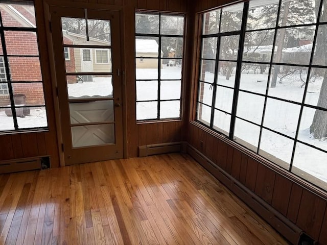 doorway with light hardwood / wood-style flooring, wooden walls, and a baseboard heating unit