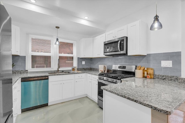 kitchen featuring appliances with stainless steel finishes, hanging light fixtures, kitchen peninsula, sink, and white cabinetry