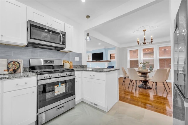 kitchen with decorative light fixtures, stainless steel appliances, and white cabinetry