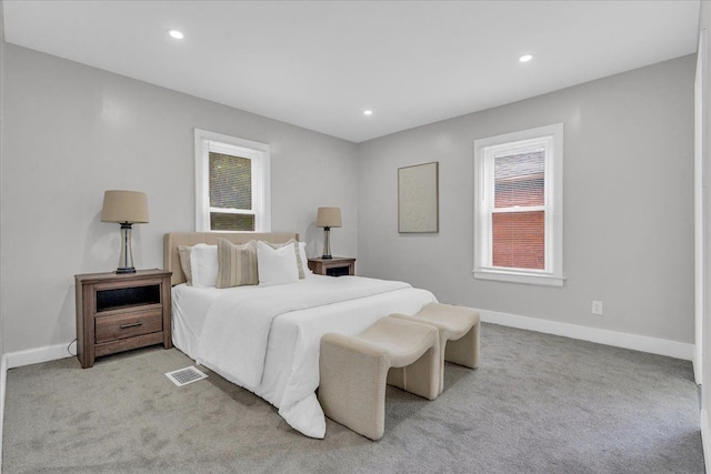 bedroom with light colored carpet and multiple windows