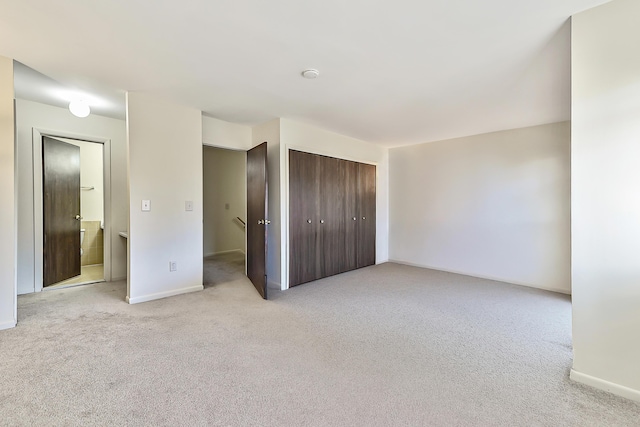 unfurnished bedroom featuring ensuite bath, a closet, and light carpet