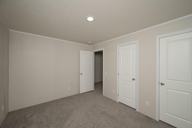 unfurnished bedroom with a textured ceiling, carpet floors, and ornamental molding