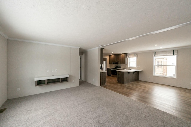 unfurnished living room featuring ornamental molding, sink, and dark carpet