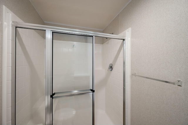 bathroom featuring crown molding and a shower with shower door