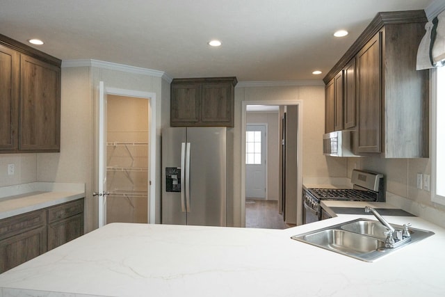 kitchen with appliances with stainless steel finishes, ornamental molding, and sink