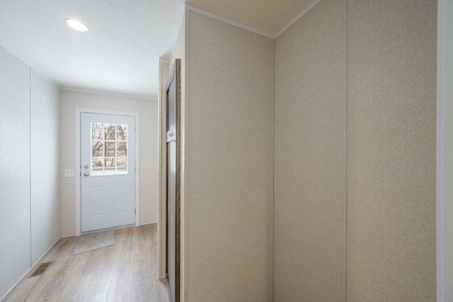 corridor with light wood-type flooring and crown molding