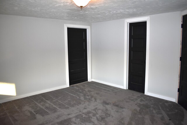 unfurnished room with a textured ceiling and dark carpet