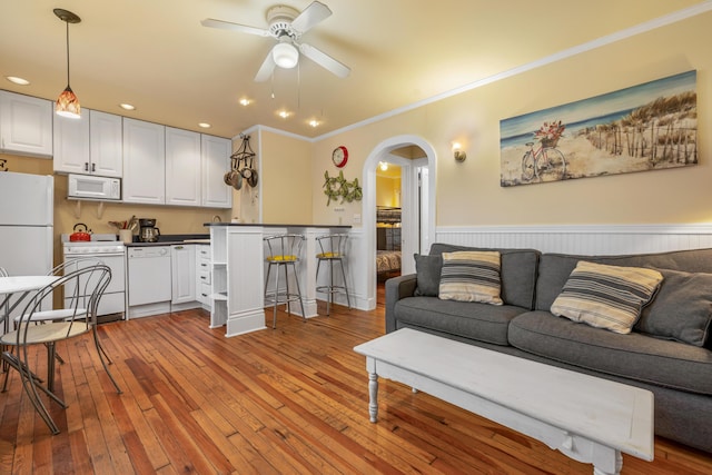 living room featuring ceiling fan, ornamental molding, and light hardwood / wood-style flooring