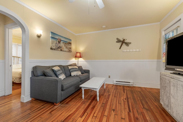 living room with a baseboard heating unit, ceiling fan, crown molding, and hardwood / wood-style floors