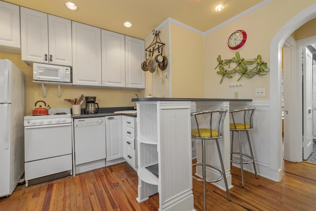 kitchen with white appliances, white cabinetry, ornamental molding, and dark wood-type flooring