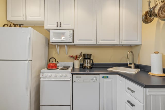 kitchen with white appliances, white cabinets, and sink