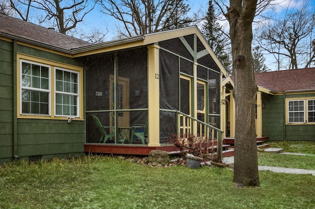 view of side of home featuring a sunroom and a lawn