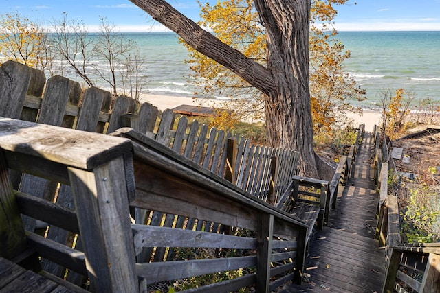 wooden terrace with a water view and a view of the beach