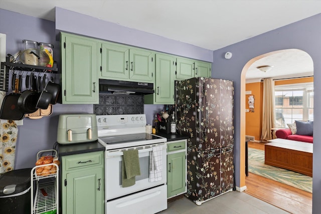 kitchen with refrigerator, electric stove, green cabinetry, and tasteful backsplash