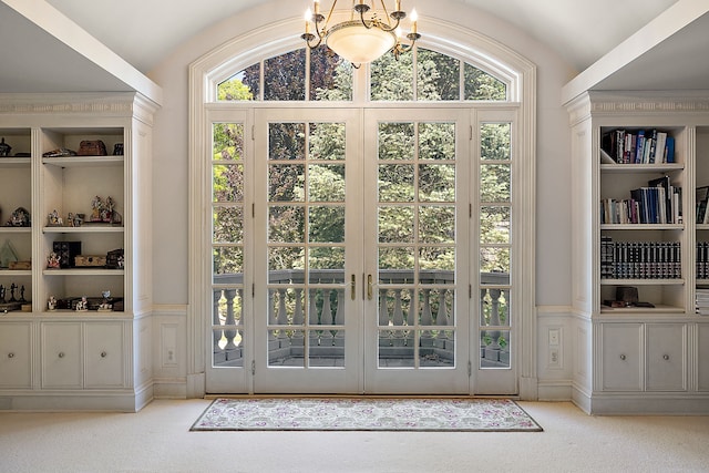 doorway to outside featuring light carpet, lofted ceiling, and a notable chandelier