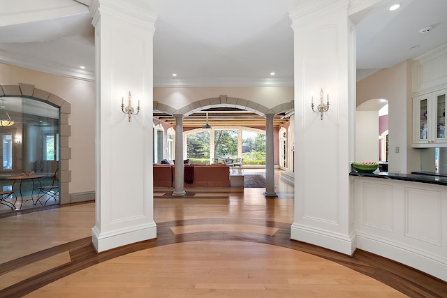 entrance foyer featuring ornamental molding, ornate columns, and light wood-type flooring