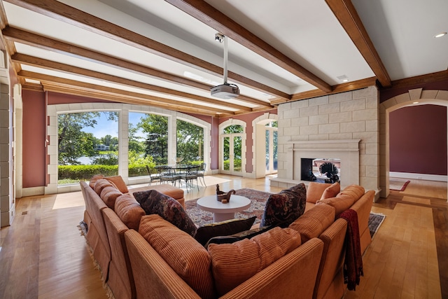 living room with light hardwood / wood-style floors, beam ceiling, ceiling fan, and a fireplace