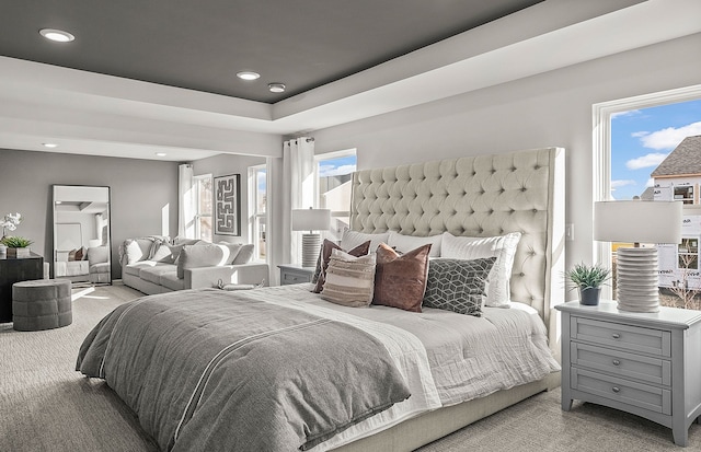 bedroom with multiple windows, a tray ceiling, and carpet