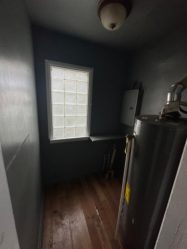 interior space with electric panel, dark wood-type flooring, and water heater