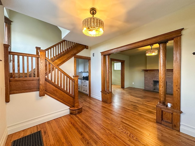 staircase featuring a notable chandelier, a brick fireplace, and wood-type flooring