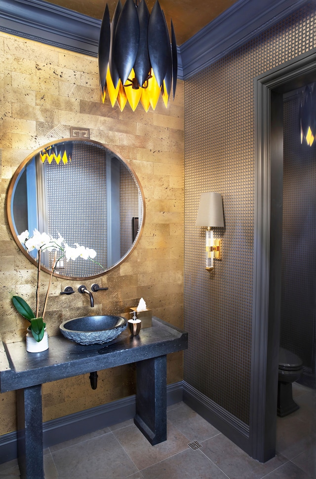 bathroom featuring toilet, wood walls, sink, and crown molding