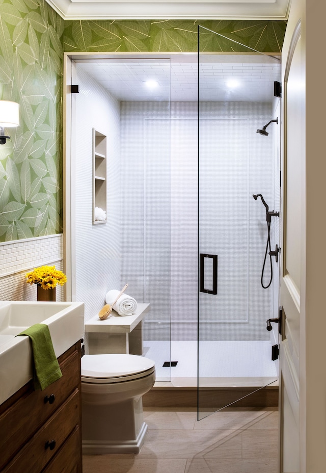 bathroom with tile patterned flooring, an enclosed shower, vanity, and toilet