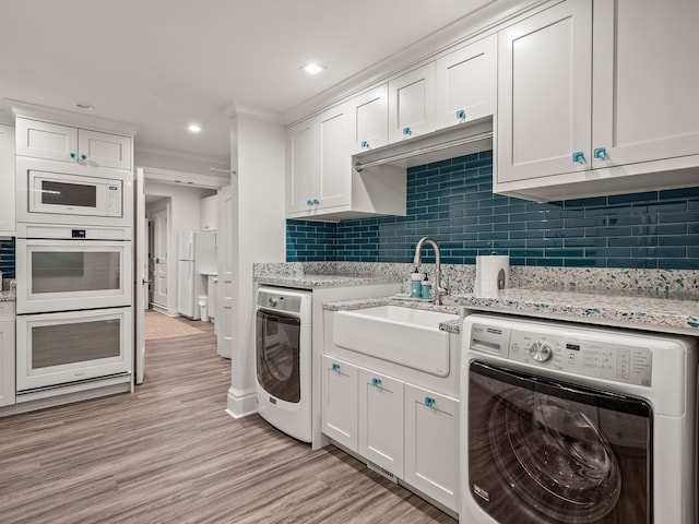 kitchen with white cabinets, washer / dryer, and sink