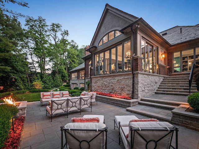 patio terrace at dusk with an outdoor living space with a fire pit