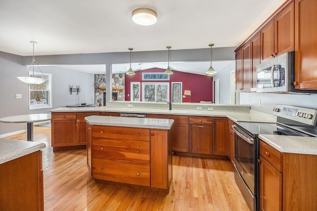 kitchen with kitchen peninsula, light wood-type flooring, appliances with stainless steel finishes, and hanging light fixtures