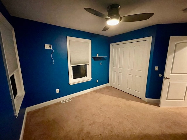 unfurnished bedroom featuring ceiling fan, a closet, and light carpet