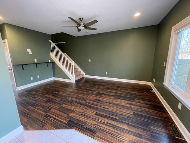 unfurnished living room featuring dark wood-type flooring and ceiling fan