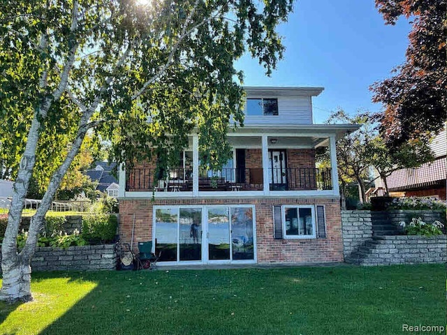 rear view of house featuring a balcony and a yard