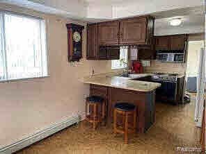 kitchen featuring a kitchen breakfast bar, electric stove, kitchen peninsula, and dark brown cabinets