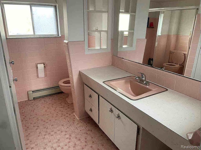 bathroom featuring tile walls, a baseboard heating unit, vanity, and toilet